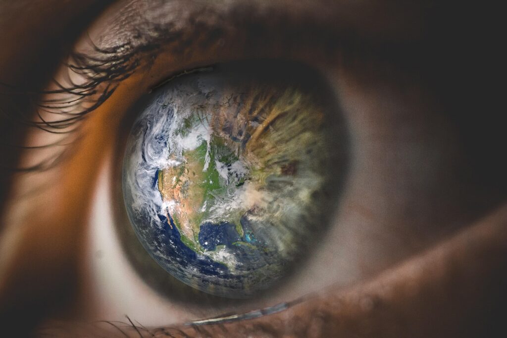 A close up picture of an eye where the world is reflected in the pupil for the blog "We see the world through the questions we’ve learned to ask" by Dhrruv Tokas.