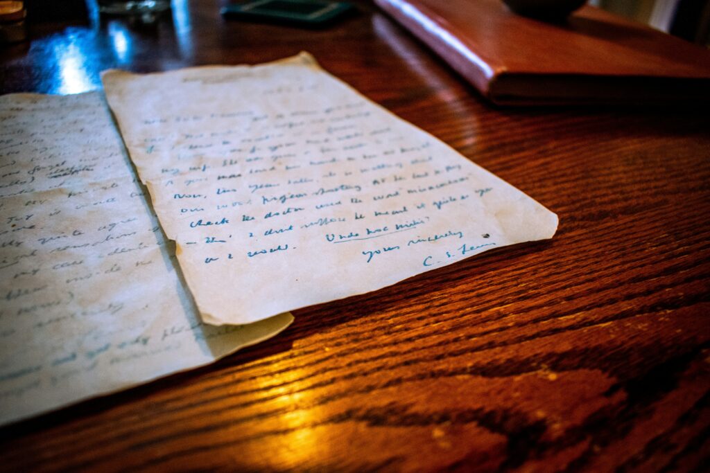 An extreme close-up shot of a handwritten letter resting on a dark wooden table, featuring a prominent name inscribed at the top. The intimate setting beautifully symbolizes identity, the labels we carry, and the quiet weight of the names we answer to, highlighting the core themes of the blog "The Name We Answer To" by Dhrruv Tokas.